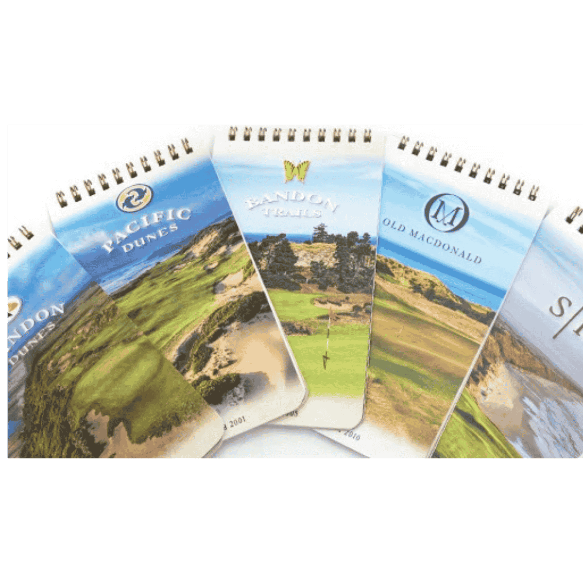 Collection of Bandon Dunes golf course yardage books fanned out showing Pacific Dunes, Bandon Trails, Old Macdonald, and Bandon Dunes covers